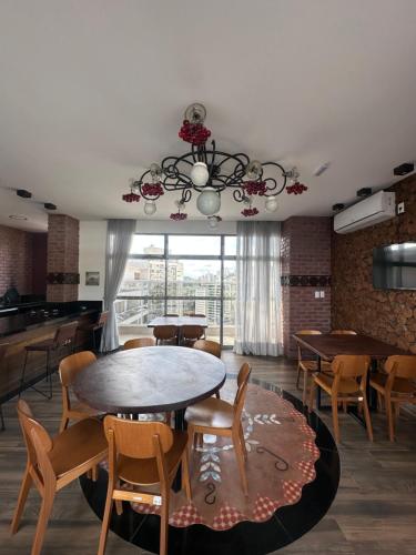 a dining room with tables and chairs and a chandelier at Stúdio Royal Central piscina/academia/coworking in Juiz de Fora