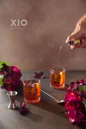 a person pouring a drink into two glasses with flowers at XIO Apartments in Bar