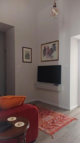 ein Wohnzimmer mit einem roten Sofa und einem Flachbild-TV in der Unterkunft ll Covo del Brigante in Melfi