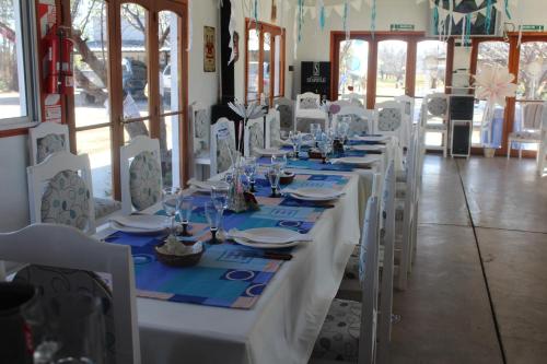 a long table with white chairs and plates and glasses at Finca La Celestita in Colonia Alvear