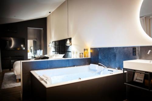 La grande salle de bains est pourvue d'une baignoire et d'un lit. dans l'établissement Hédoné Suite de luxe et Spa privatif, à Nancy