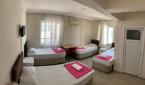 Zimmer mit 3 Betten und einem Tisch mit rosa Bettwäsche in der Unterkunft Ayberk Pansiyon in Canakkale