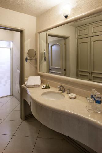 a bathroom with a sink and a large mirror at Hotel & Suites Quinta Magna in Guadalajara
