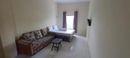 a living room with a couch and a bed at Solo Nadamax City Guest House Syariah in Bonorejo