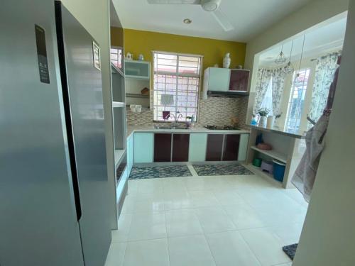カンガーにあるDaffodil Homestay in Perlisの白いタイルフロアのキッチン(冷蔵庫付)