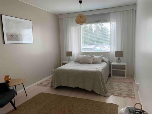 a white bedroom with a bed and a window at 3 h + keittiö ja parveke, juuri remontoitu! in Lahti
