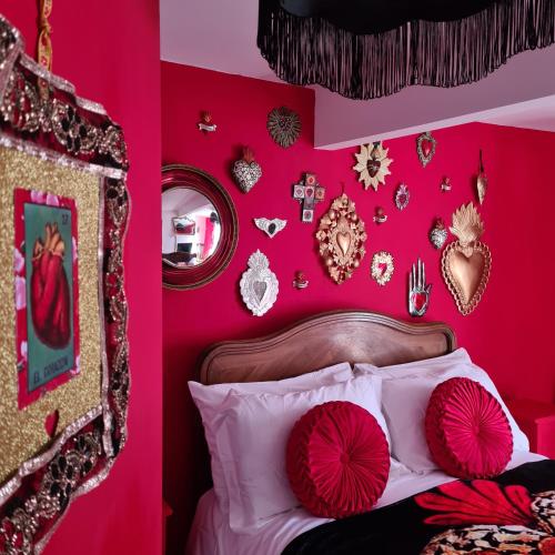 a bedroom with pink walls and a bed with red pillows at Frida's Cottage Whitby in Whitby