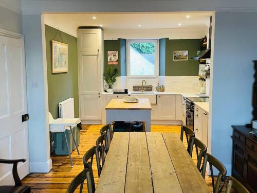 a large kitchen with a wooden table and chairs at Beautifully restored beach side Victorian house! in Torcross