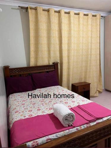 a bedroom with a bed with a hawkish homes sign on it at Havilla homes in Kitengela 