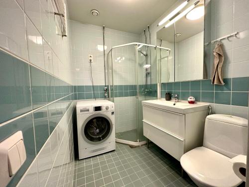 uma casa de banho com uma máquina de lavar roupa ao lado de um WC em Cosy flat in the heart of Helsinki center em Helsinque