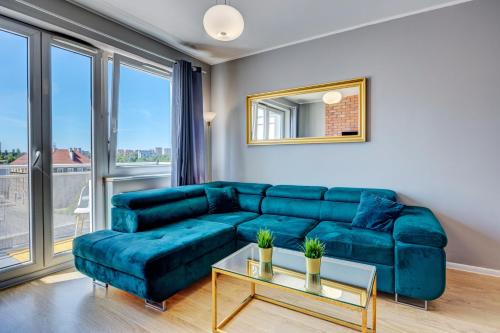 Allure Nautica Aparthotel في شتتين: غرفة معيشة مع أريكة زرقاء وطاولة