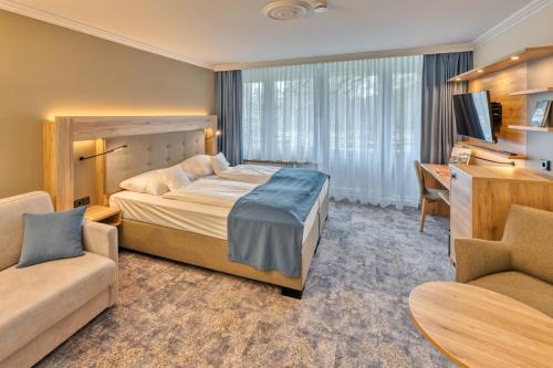 - une chambre avec un lit, un bureau et un canapé dans l'établissement Ringhotel Ahrensburg, à Ahrensburg