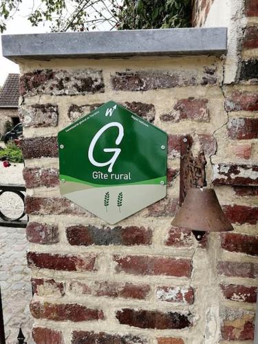a green and white sign on a brick wall at Gite rural La Ferme du Semeur-Zaaiershof in Lessines