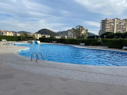 une grande piscine d'eau bleue dans une ville dans l'établissement Studio Eleverca 3*- rez de jardin terrasse - Axelle Loc'Appart, à Mandelieu-la-Napoule