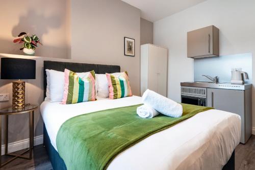 um quarto com uma grande cama branca com almofadas coloridas em Fulham Studio Apartments em Londres