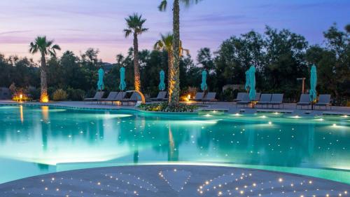 a pool with chairs and palm trees at night at Hotel Abi d'Oru in Porto Rotondo