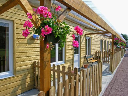 a wooden house with a fence and flowers on it at Gite Caillebourg Normandie in Saint-Martin-aux-Arbres