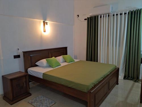 1 dormitorio con 1 cama con almohadas verdes y blancas en Dickwella Green Villa, en Dikwella