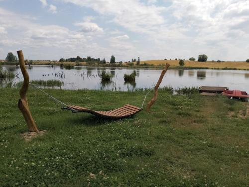 a hammock sitting in the grass next to a lake at Domek Nad Stawem in Gołdap