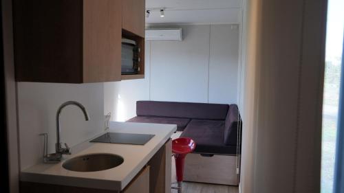 a small kitchen with a sink and a stool at Cabañas y Padel Tinycolchagua cl in Santa Cruz
