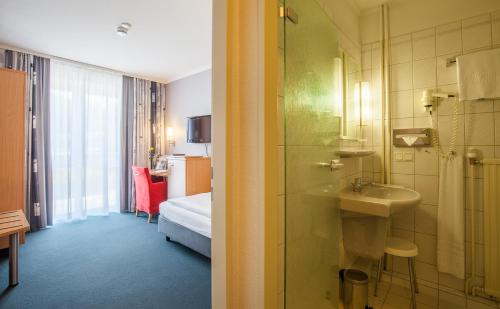 Dieses Zimmer verfügt über ein Bad mit einem Waschbecken und einer Dusche. in der Unterkunft Ringhotel Ahrensburg in Ahrensburg