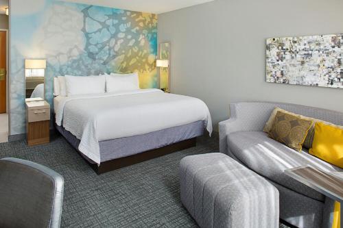 a hotel room with a bed and a couch at Courtyard by Marriott Battle Creek in Battle Creek