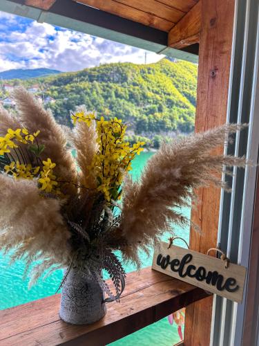 a vase of flowers on a window sill with a welcome sign at Edison in Jablanica