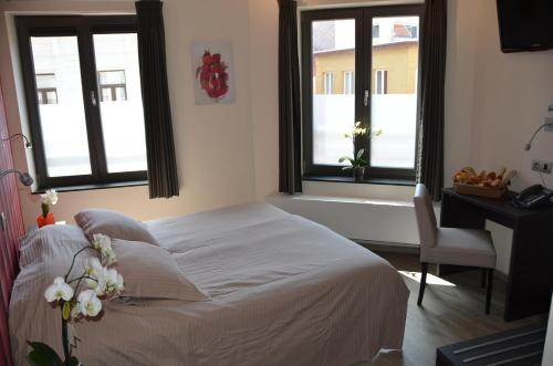 a bedroom with a bed and a desk and windows at Logies Bocadillo in Blankenberge