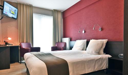 Habitación de hotel con cama grande y pared roja en Logies Bocadillo, en Blankenberge