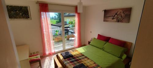 a bedroom with a green bed and a window at Casa Diana Locarno-Cugnasco in Locarno