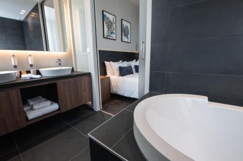 a bathroom with a tub and a sink and a bed at Best Western Premier Le Chapitre Hotel and Spa in Remiremont