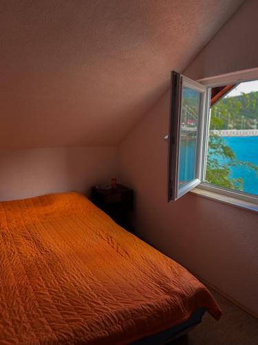 1 dormitorio con cama de color naranja y ventana en Edison, en Jablanica