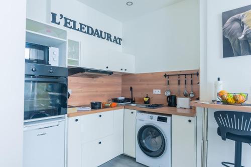 cocina con armarios blancos, lavadora y secadora en L' éléDaurat : Studio Haut Standing Riom Centre en Riom