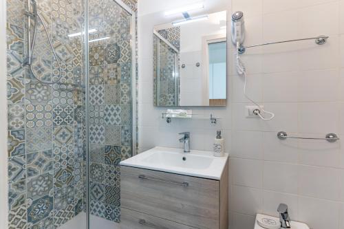 uma casa de banho com um lavatório e um chuveiro com um espelho. em Doctor Guest House em Tortolì