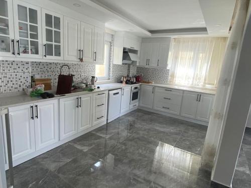 uma grande cozinha branca com armários brancos e pisos em mármore em Villa Venus em Gazipasa