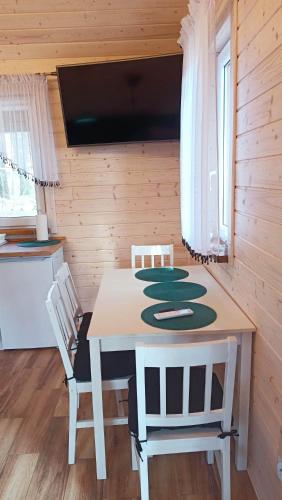 a dining room table with two chairs and a television at Domek Nad Stawem in Gołdap