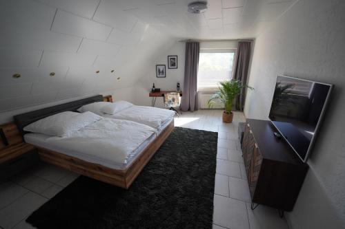 Schlafzimmer mit einem Bett und einem Flachbild-TV in der Unterkunft "SANO" Apartments - Herdecke - Maisonette - Balkon - Tiefgarage in Herdecke