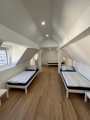 two beds in a attic room with wooden floors at Modernes Haus 5 Min vom See in Waldsee