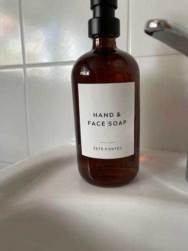 a bottle of hand soap sitting on a bathroom sink at Sete Fontes - Agarone Holiday Nest in Agarone