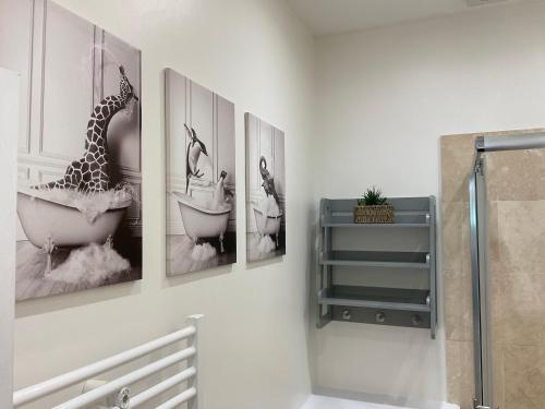 ein Badezimmer mit drei Bildern einer Giraffe in einer Badewanne in der Unterkunft 2 bed Home from Home Apartment 41 in London