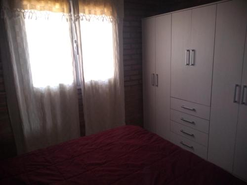 a bedroom with a bed and a window with curtains at La Lechuza in El Volcán