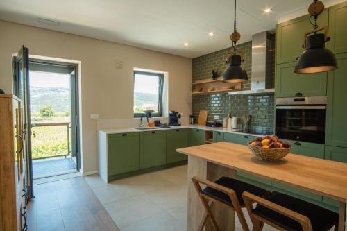 a kitchen with green cabinets and a table with a bowl of fruit at Casa de Algar - Enoturismo in Castelo de Paiva