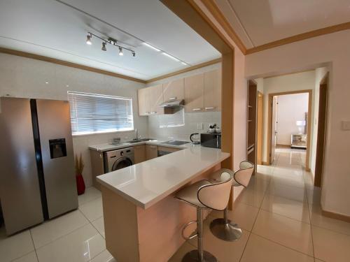 a kitchen with a large white counter and chairs at Siena Sun Luxury Apartment 6 in Midrand