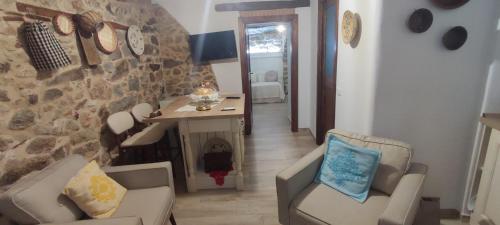 a living room with chairs and a desk and a stone wall at Antica Fonni in Fonni