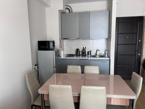 a kitchen with a pink table and white chairs at Nino's Sunny Apartment in Bakuriani