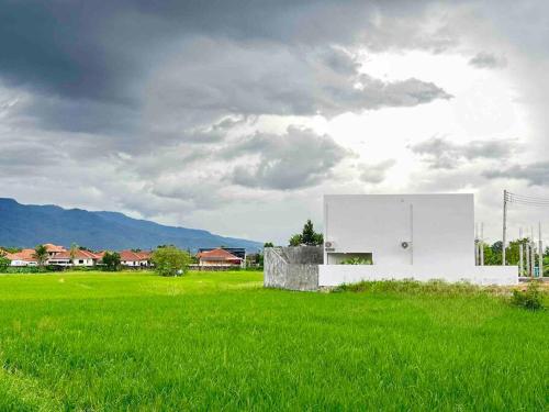 um edifício branco num campo de relva verde em The Rice Villas วิวทุ่งนาภูเขา 2King beds& hot Bathtub em San Sai