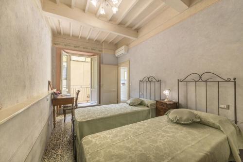 um quarto com 2 camas, uma secretária e uma janela em I Bei Ricordi - Historic Centre Apartment 6 em Arezzo