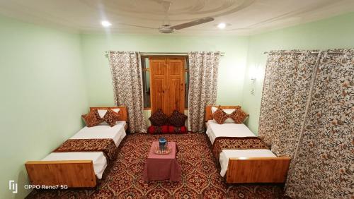 a room with two beds and a table in it at Moonshine Homestay Kashmir in Srinagar