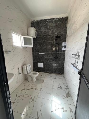 a white bathroom with a toilet and a sink at AbCd in Nouakchott