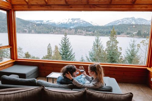 duas pessoas sentadas numa sala com uma grande janela em Peninsula Petit em San Carlos de Bariloche